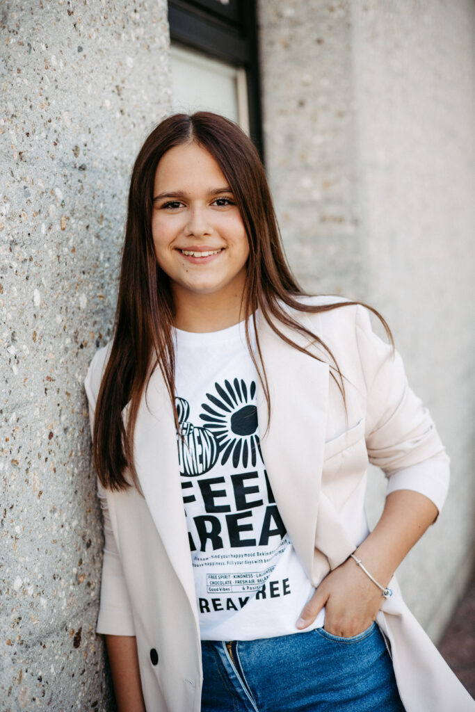 Junge Frau wird für die Bewerbung portraitiert. Bewerbungsfoto ganz locker und freundlich. Das Bewerbungsshooting fand draußen statt. Mit vorheriger Absprache um die perfekte Location zu finden