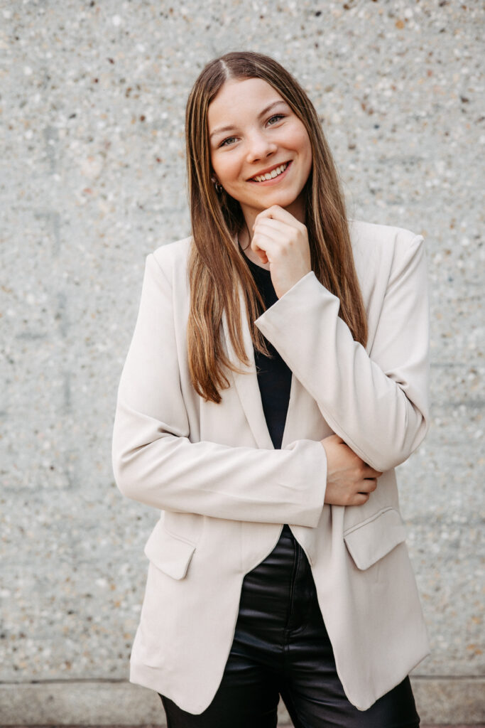 freundliches, offenes Bewerbungsfoto. Die Person trägt helle Farben und lächelt glücklich in die Kamera. Perfektes Businessfoto
