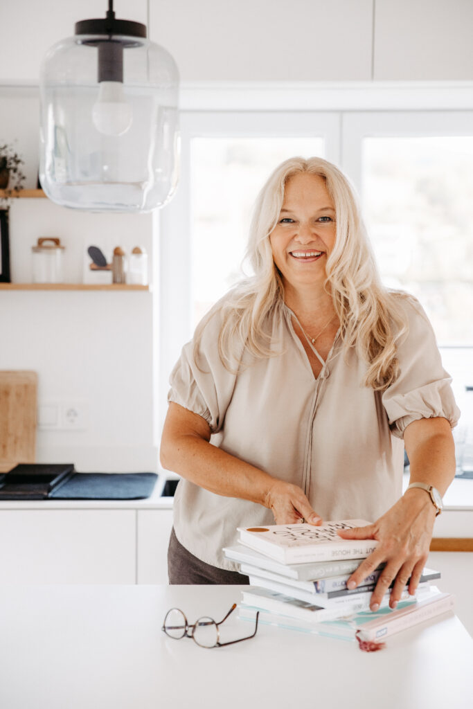 Businessshooting. Frau bei der Arbeit im gewohnten Arbeitsumfeld. Das Bild ist ruhig und stimmig in hellen, neutralen Farben. Die Person ist freundlich und lächelt. Authentische und echte Berufsbilder oder Businessbilder