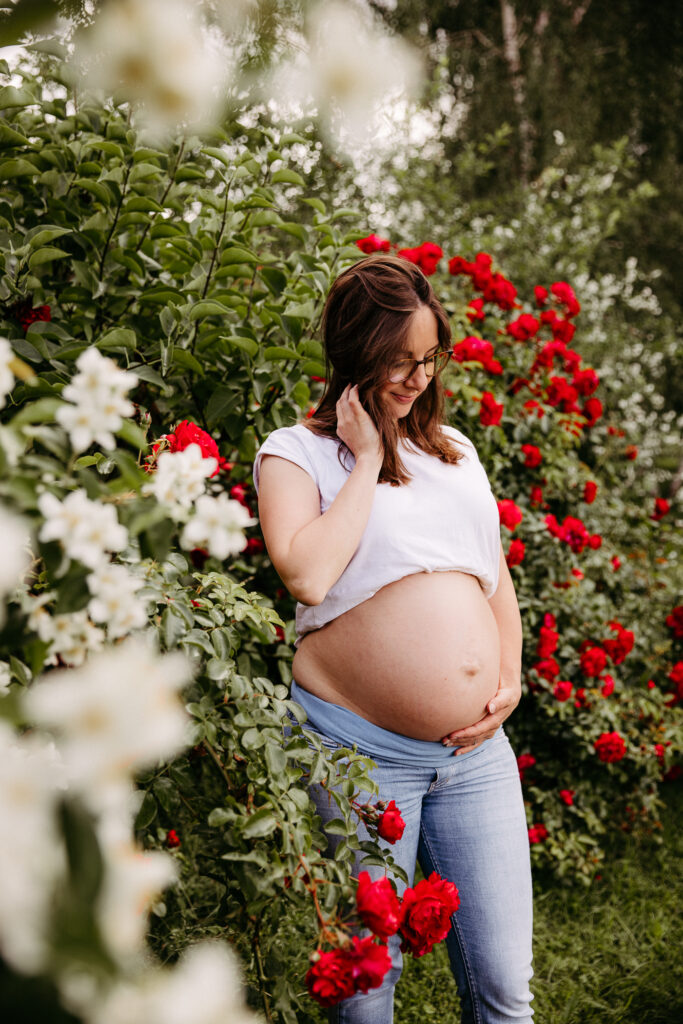 babybauch im Blumenmeer, Schwangerschaftsshooting zwischen roten Rosen